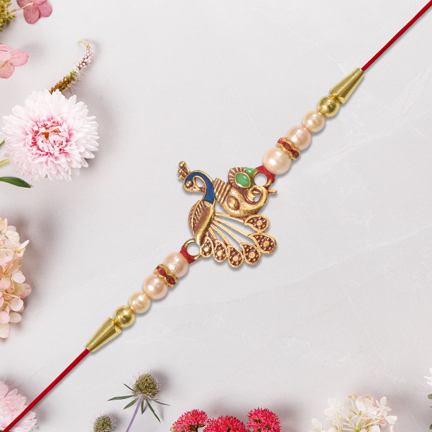 Elegant Peacock Design Rakhi with Pearl Beads and Golden Detailing on Red Thread