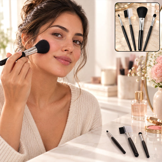 A woman applies blush with a large black and silver makeup brush, with three other brushes and a mirror on the table.