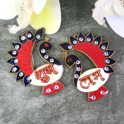 Two colorful peacock-shaped Shubh Labh wall hangings with red, blue, and white enamel, adorned with clear rhinestones.
