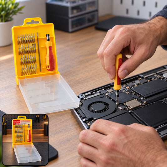 A person uses a yellow and red screwdriver from a 32-piece set to repair a laptop on a wooden desk.