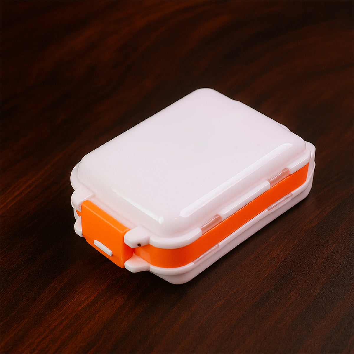 Close-up of secure snap locks on orange dual-sided pill organizer