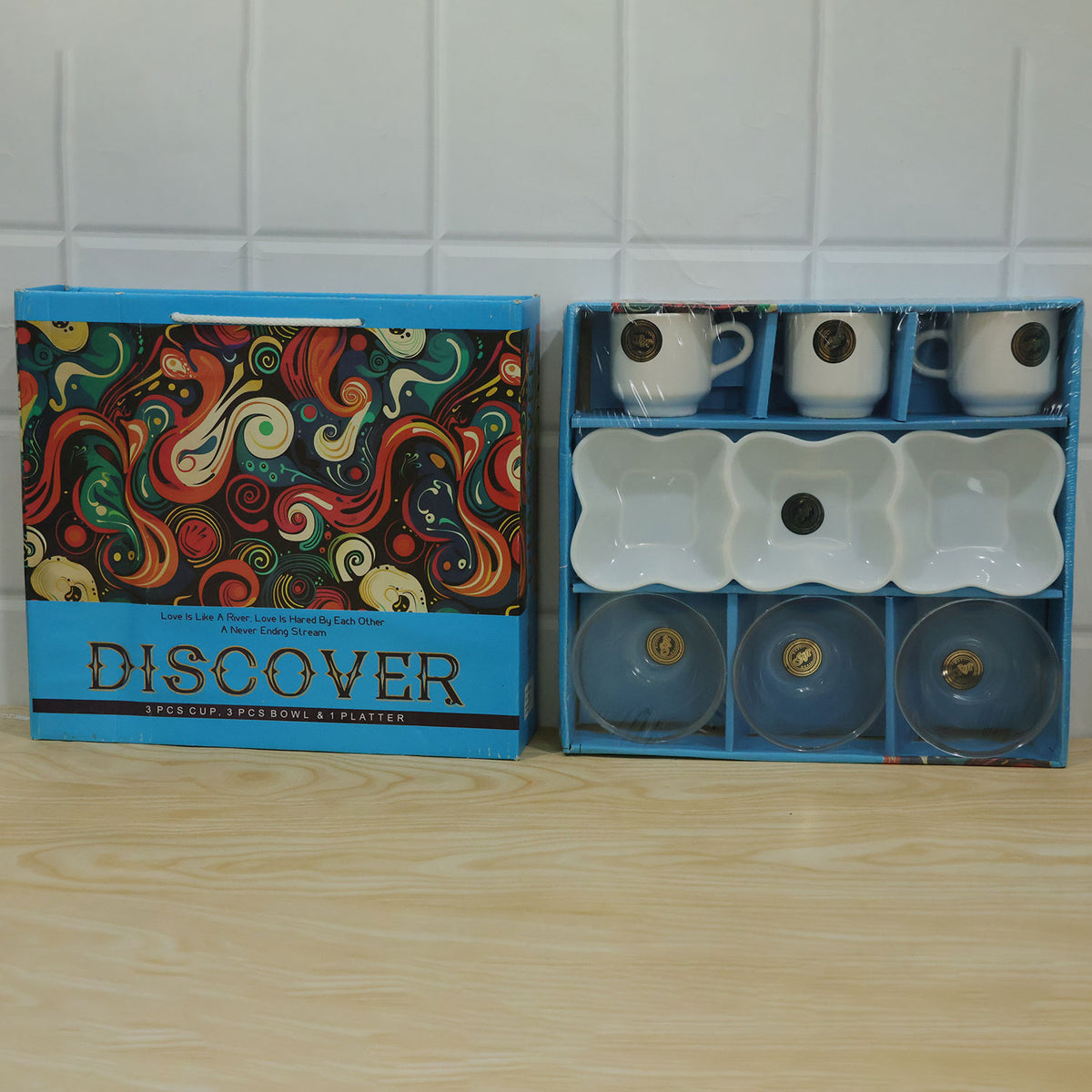 The blue gift box with its colorful lid is shown next to the open box, revealing the seven-piece serving set neatly