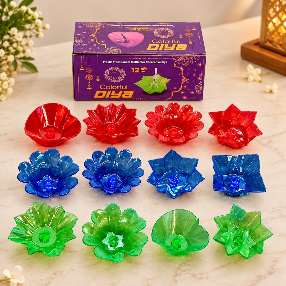 A purple box of 12 colorful diyas, with red, blue, and green plastic diyas arranged around it.