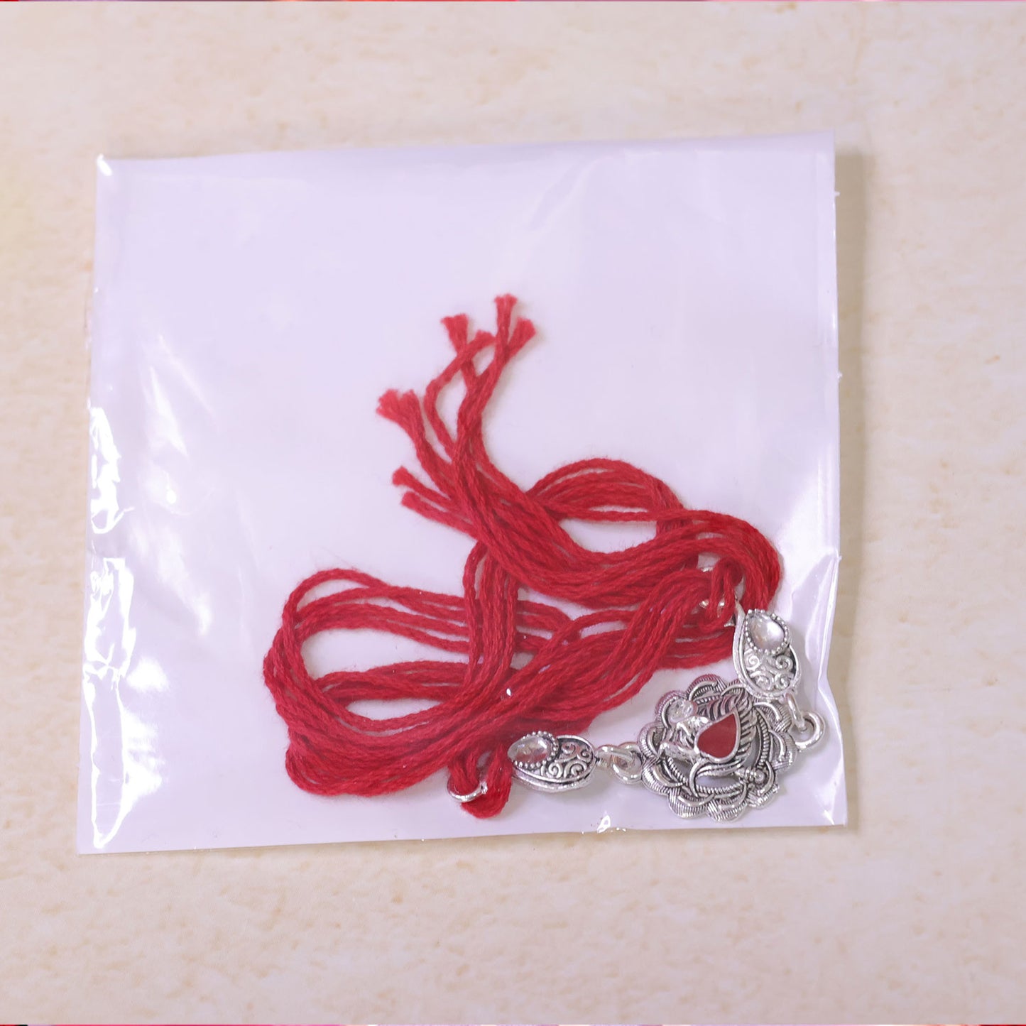 Ornate Rakhi featuring Silver Round Charm, metal trims and chain look for Gifting
