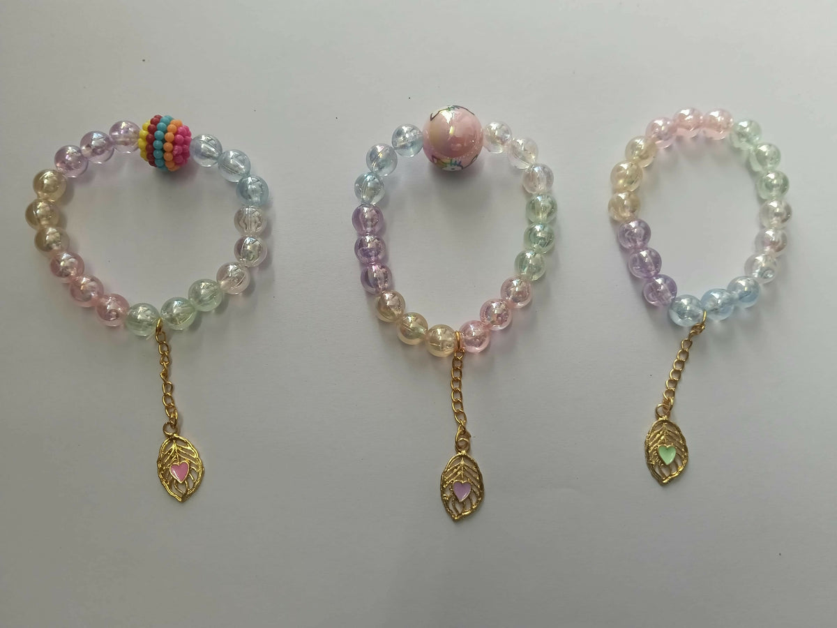 Three pastel beaded bracelets with gold leaf charms, each having a unique central bead, displayed on a plain white surface.
