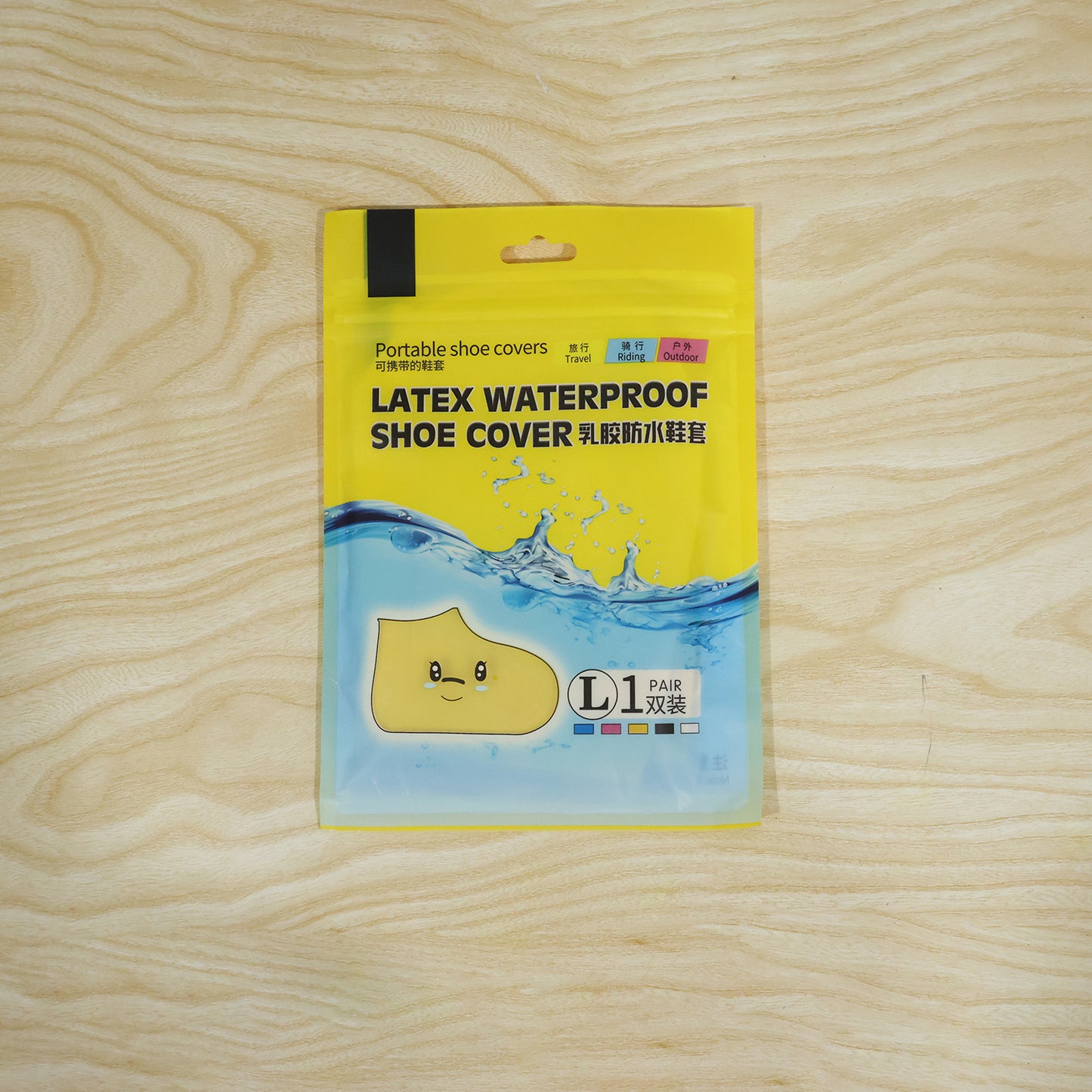 A yellow plastic package for "Latex Waterproof Shoe Cover" with a cartoon shoe and size L is on a wooden surface.
