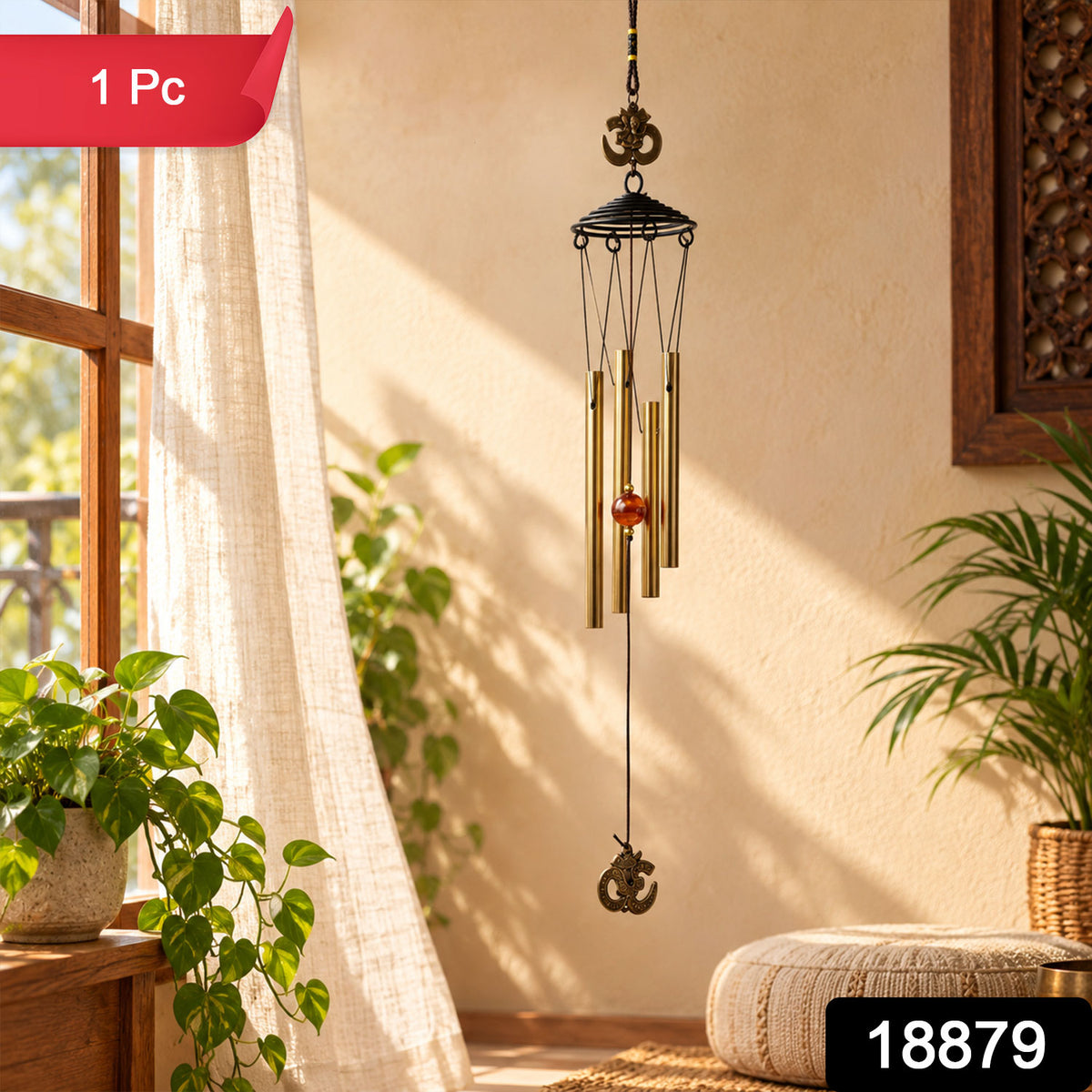 A metal wind chime with five gold-toned tubes and Om symbols, hanging beside a window with sheer curtains and a – view 2