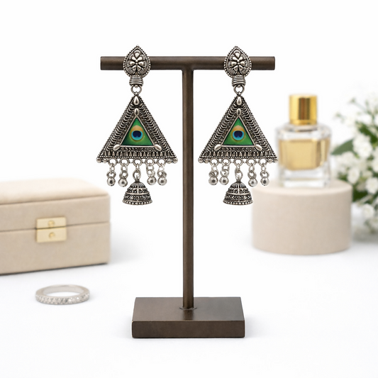 Close-up of oxidized silver peacock jhumka earrings with detailed tribal carvings