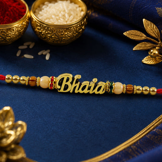 Close up of golden Bhaiya Rakhi with peach brown beads and red thread.