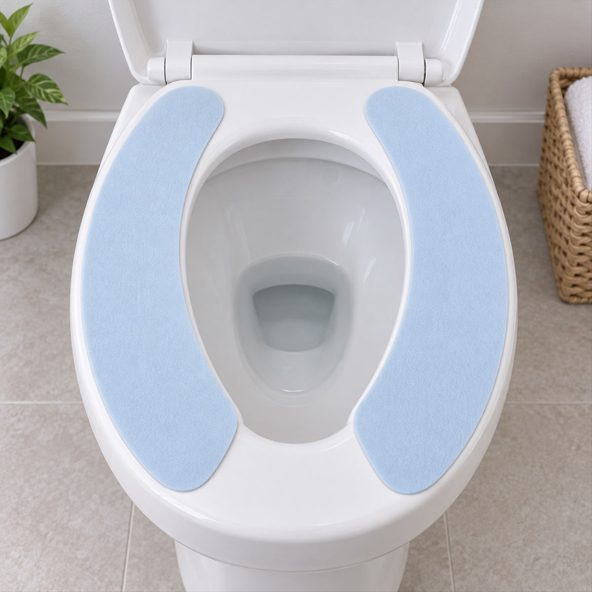 Two light blue fabric pads are positioned on a white toilet seat, ready for use in a clean bathroom.