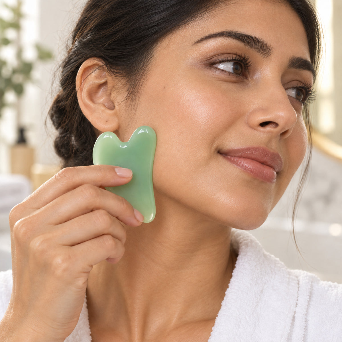 Curved gua sha tool used along cheek