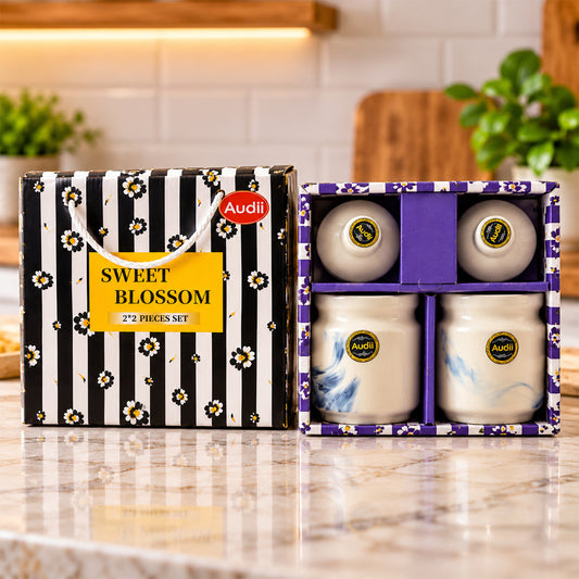 A black and white striped gift box with a yellow label and two ceramic jars in a purple box.