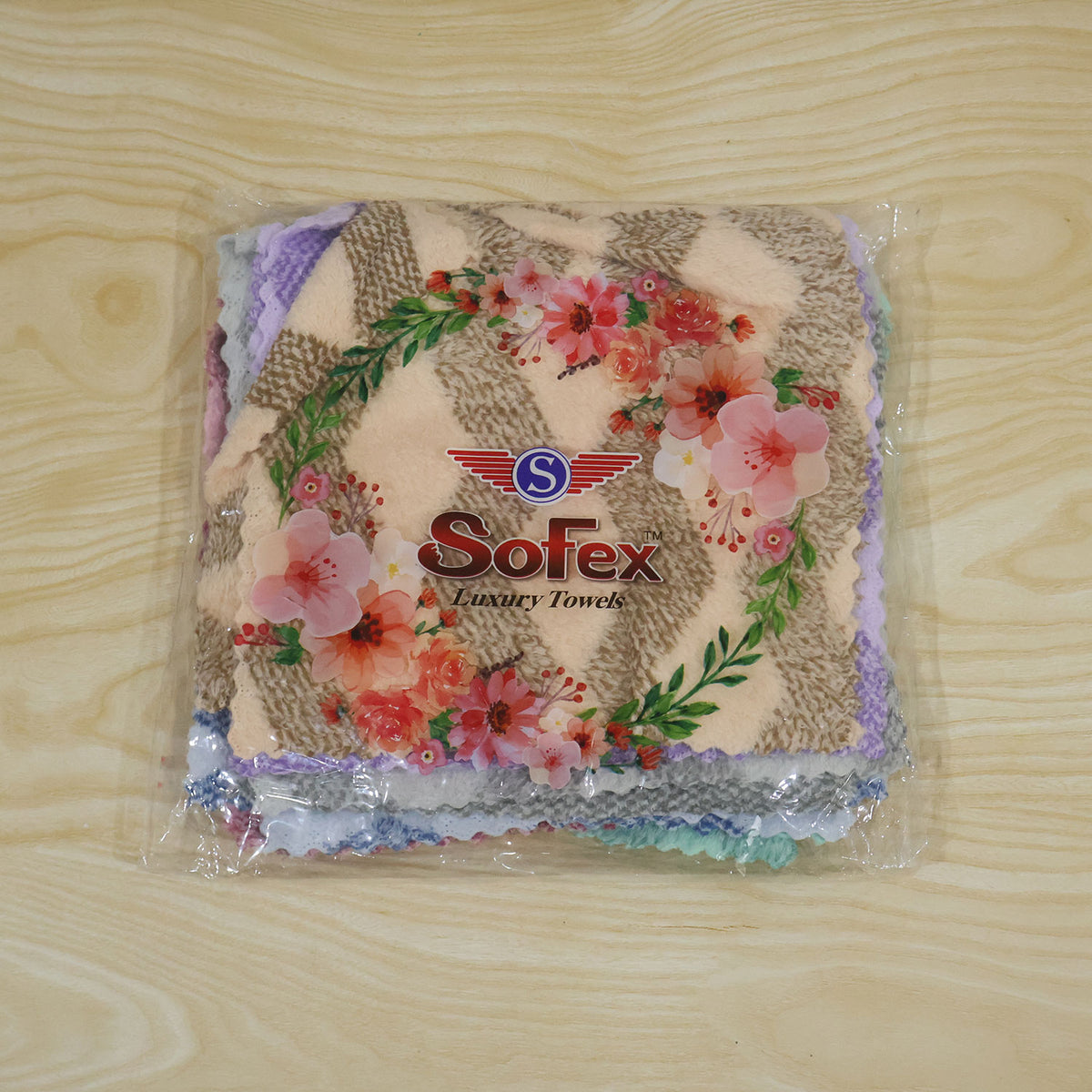 A clear plastic package of assorted pastel chevron towels with a floral design and brand logo on a wooden surface.