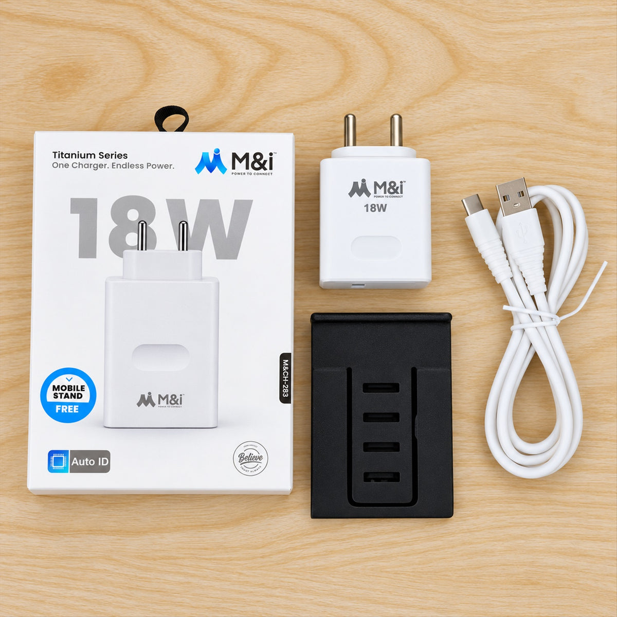 White box, white 18W charger, black mobile stand, and white coiled cable on a wooden surface.