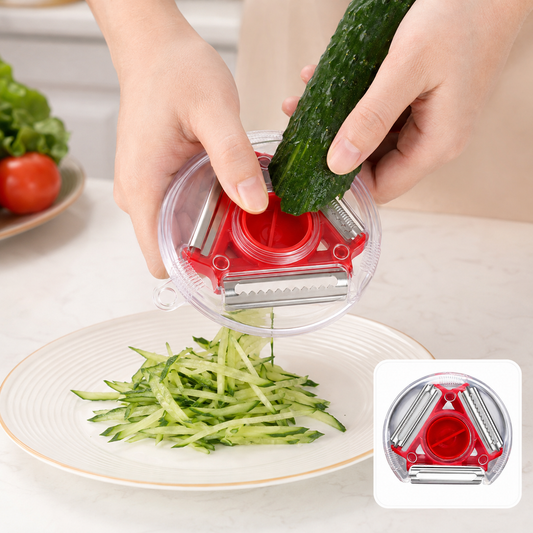 A person uses a red and clear rotary peeler to julienne a cucumber into a pile on a white plate.