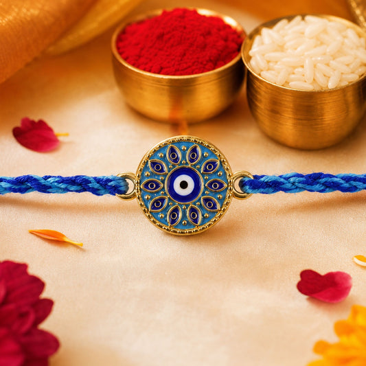 A blue and gold evil eye bracelet on a gold cloth with red powder and white rice in brass bowls.