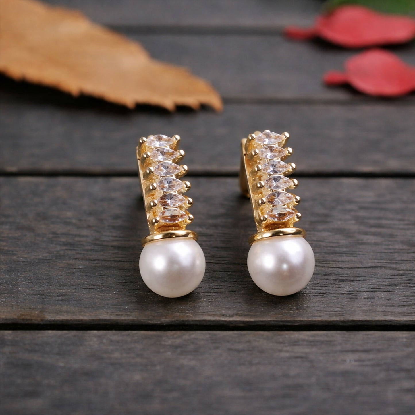 Elegant pearl drop earrings with sparkling stones and gold finish in vertical arrangement