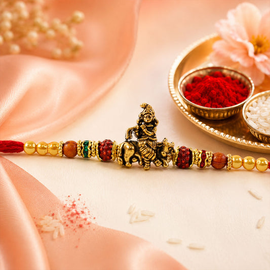 Bal Krishna Rakhi with golden idol centre and red bead accents on a white background.