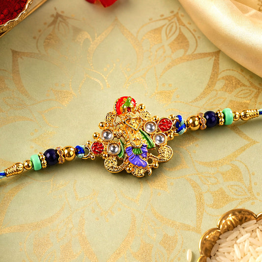 A gold-colored, ornate deity charm with colorful enamel and beads on a blue and green braided thread.