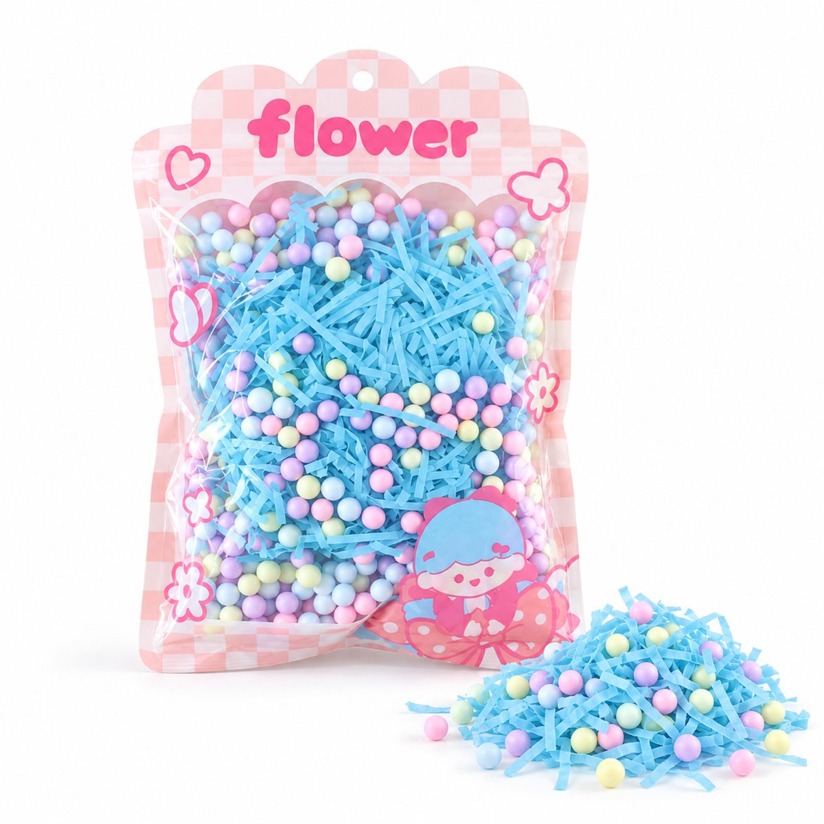 A clear bag of blue shredded paper and pastel foam balls stands beside a small pile of the same materials.