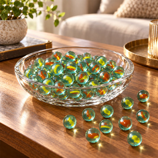A clear glass bowl filled with numerous translucent green marbles, each containing yellow and red swirls, resting on a