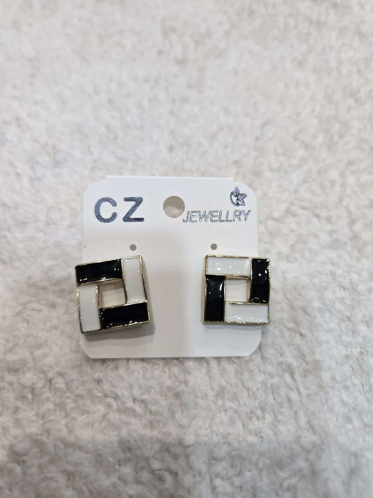 A pair of black and white square earrings displayed on a white jewelry card.