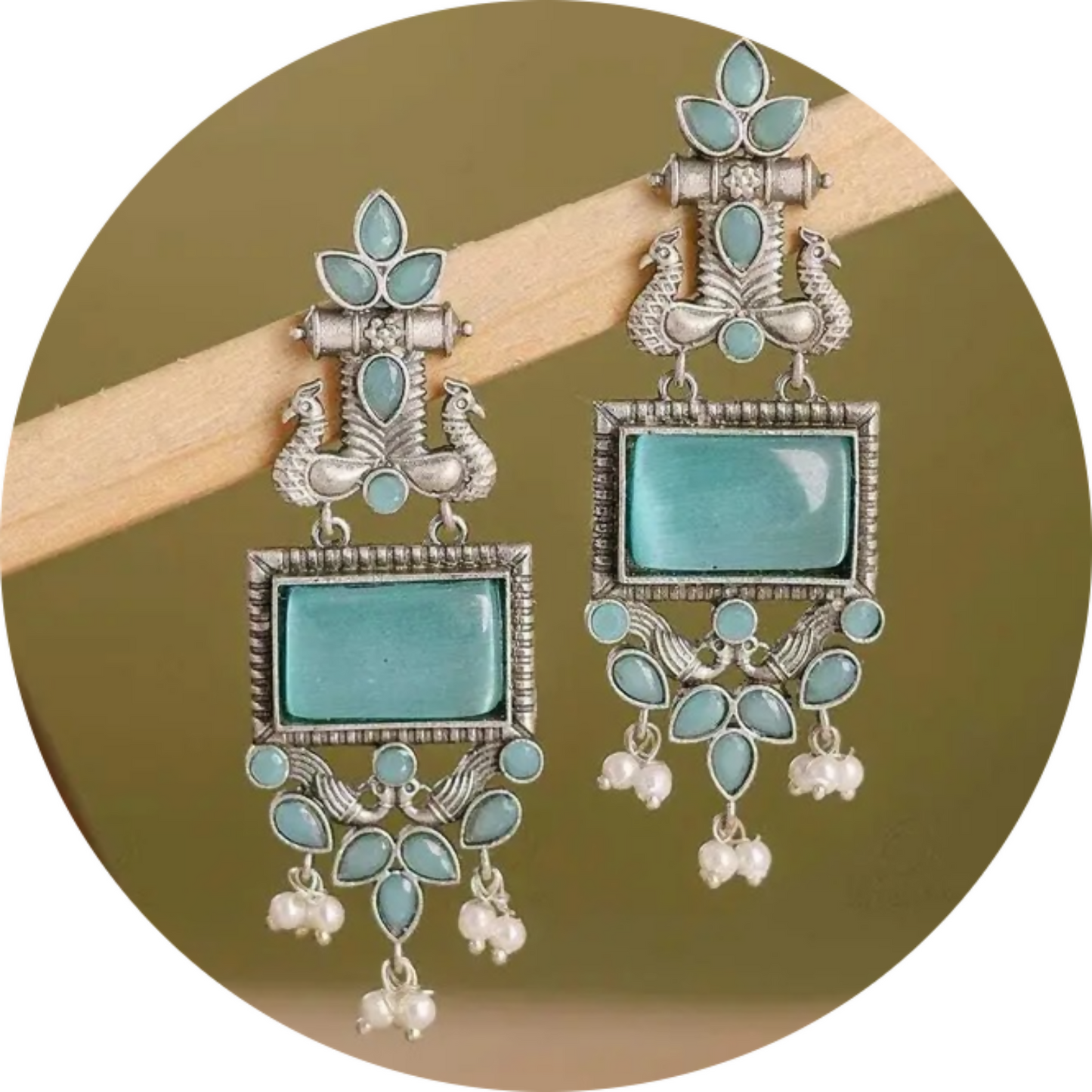 Side view of oxidized silver earrings with vibrant blue stones and pearl accents