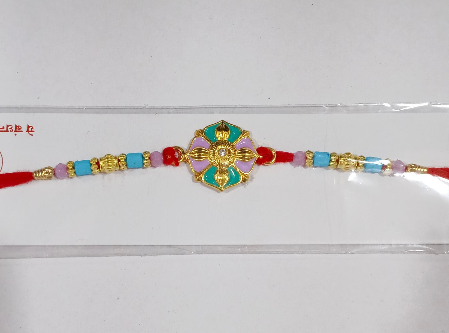 Styled image of Flower Motif Rakhi with colorful beads on festive background