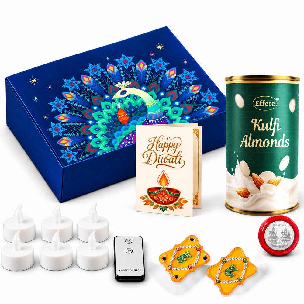 A blue gift box with a peacock design, a can of Kulfi almonds, a Diwali card, tealights, a remote, and red and yellow Shubh