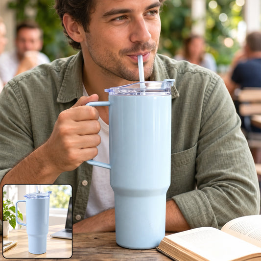 A man sips from a large light blue handled tumbler with a straw at an outdoor cafe.