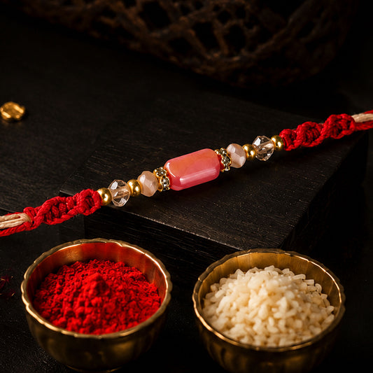 Sparkling pearl stone rakhi with colourful thread displayed on a wrist.