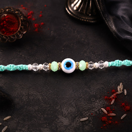 Close-up of Blue Evil Eye Nazar Charm Rakhi with turquoise thread and beads on a white background.