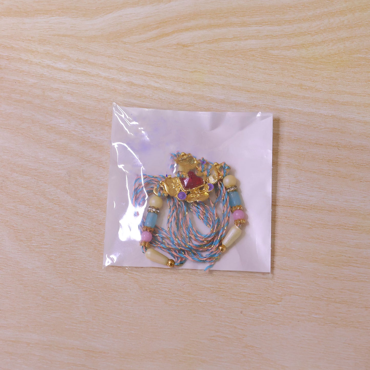 Ornate Rakhi showcasing Square Crystal Charm, gift finish and chain look for Gift Use