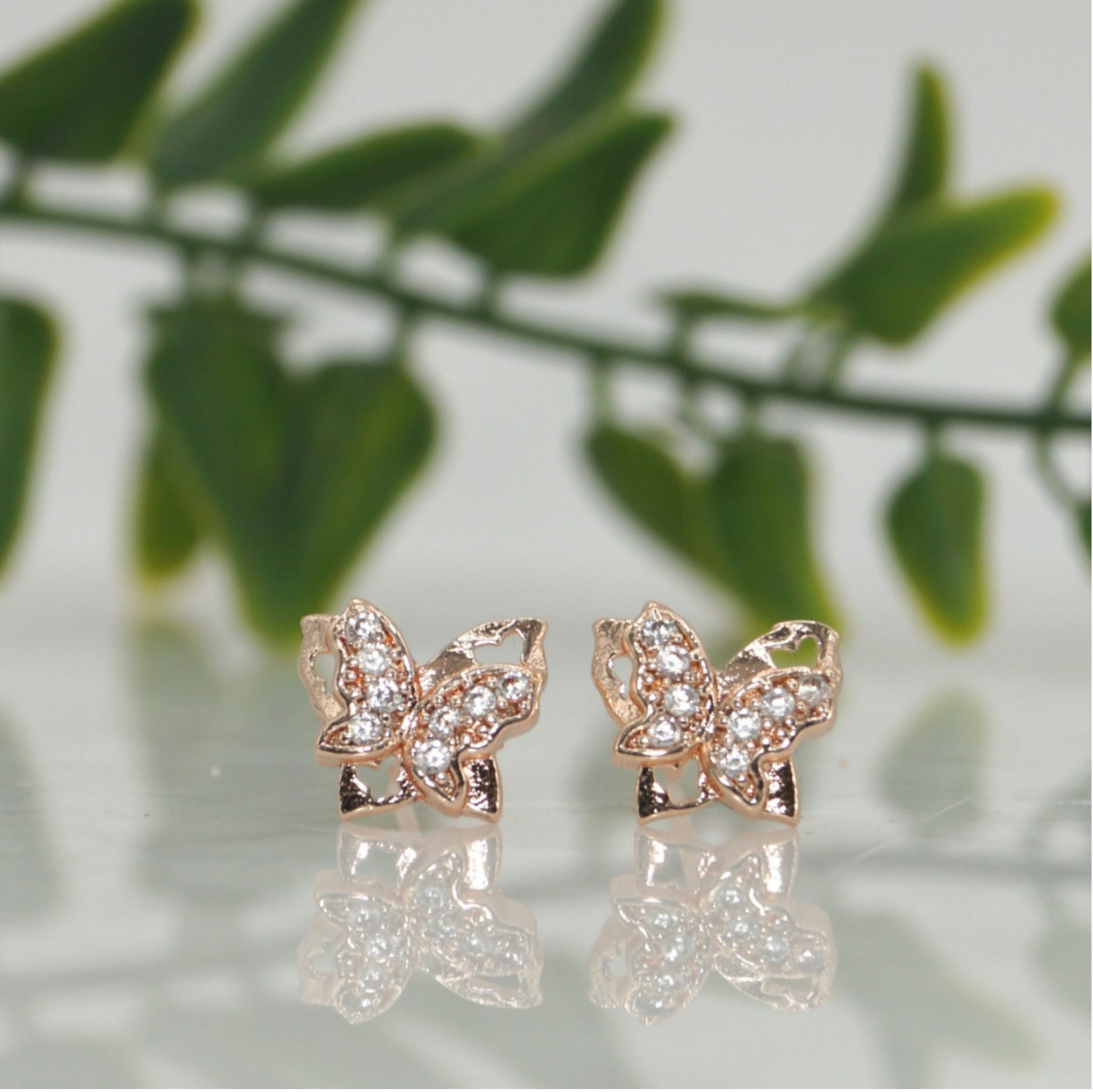 Close-up of rose gold pave butterfly stud earrings sparkling with cubic zirconia stones