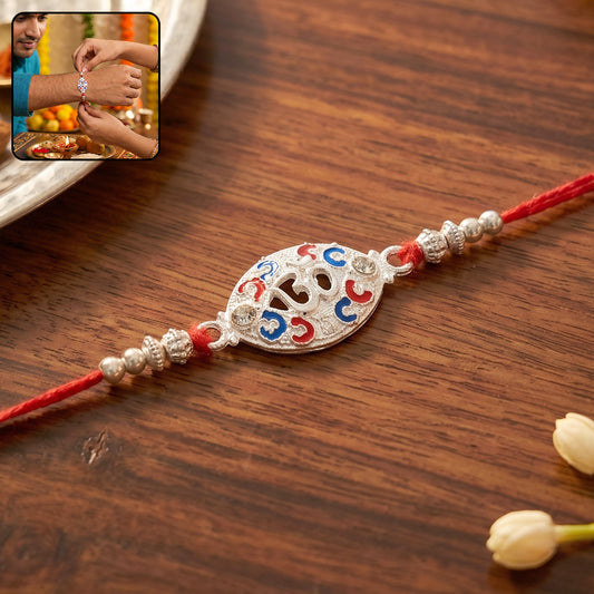 Silver Om Rakhi with red thread on white background