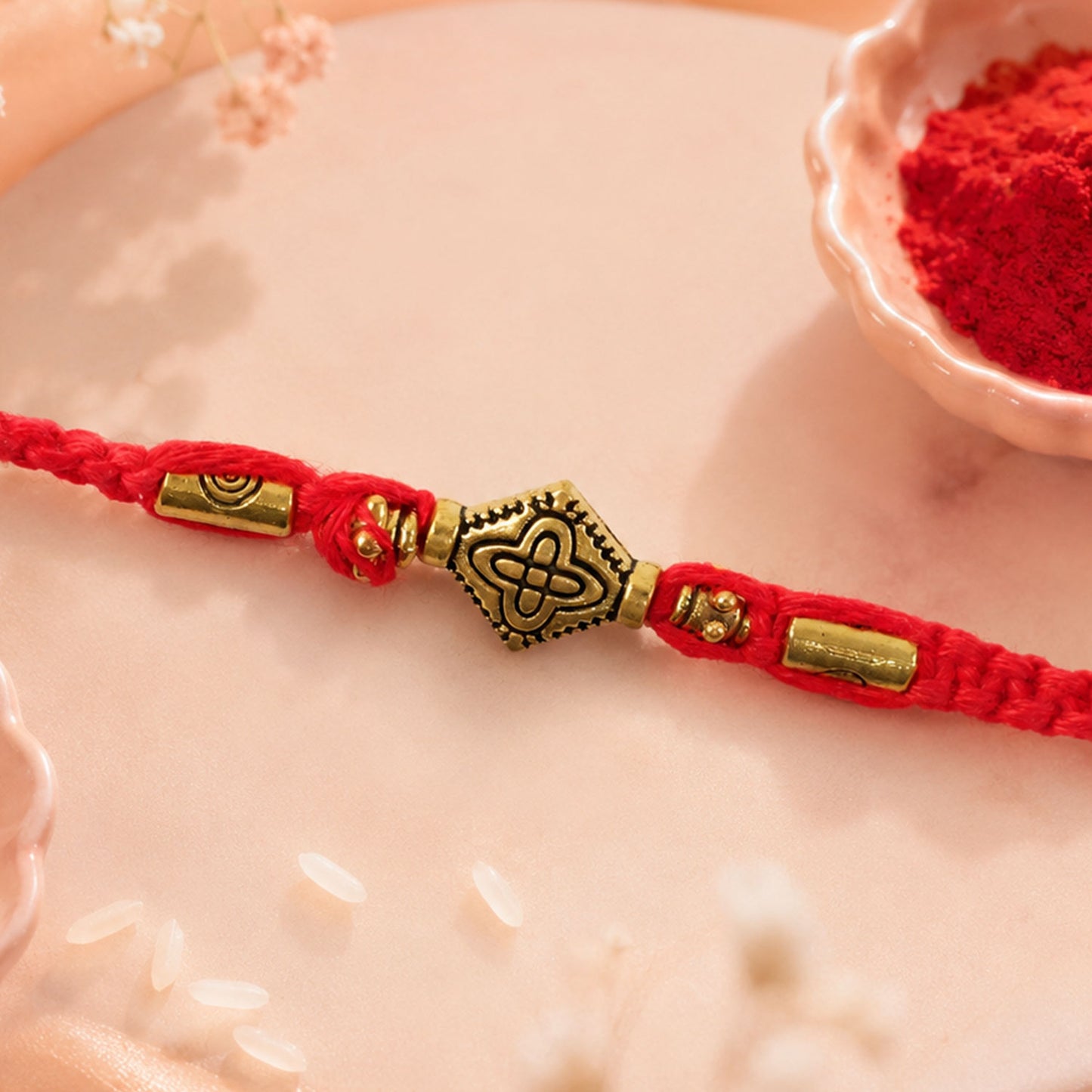 Red Thread Rakhi with an Intricately Detailed Antique Gold Charm