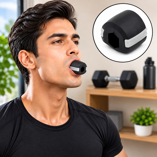 A man with dark hair and a black t-shirt uses a black and white jaw exerciser in his mouth.