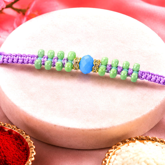Purple macrame rakhi bracelet with green beads and blue accent, close-up view.