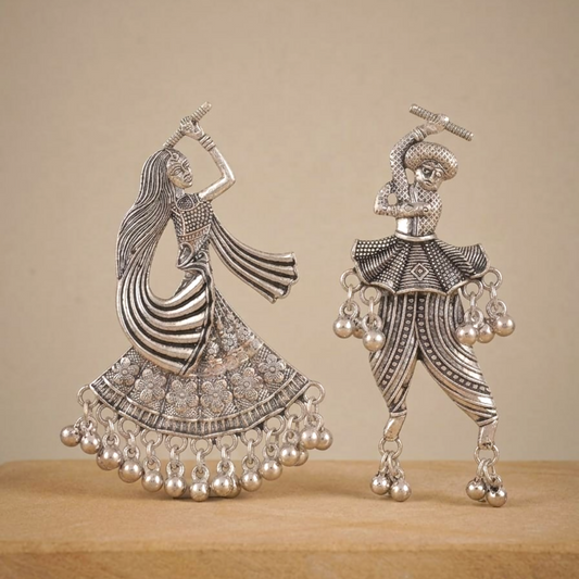 A pair of oxidized silver earrings depicting a female and male tribal dancer with ghungroo details.
