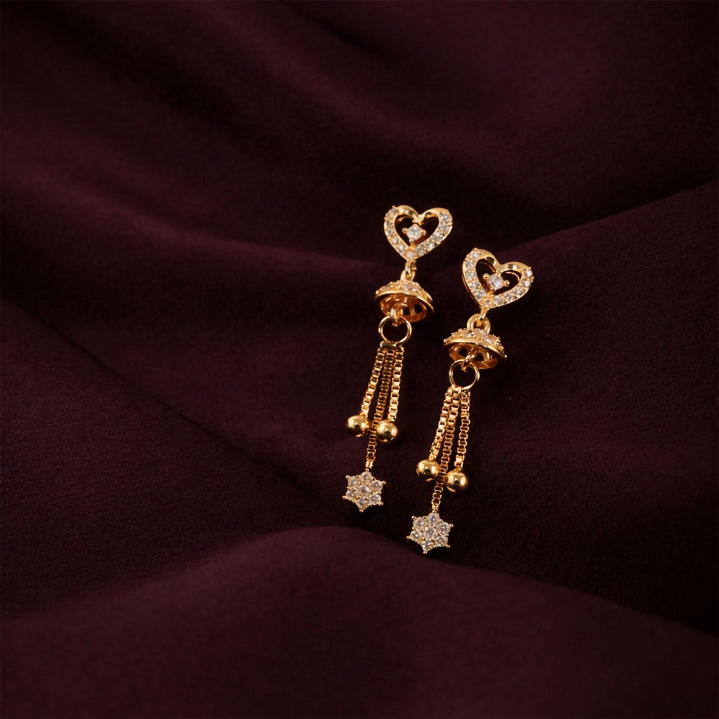 Close-up image showing fine crystals on open heart design of gold plated earrings