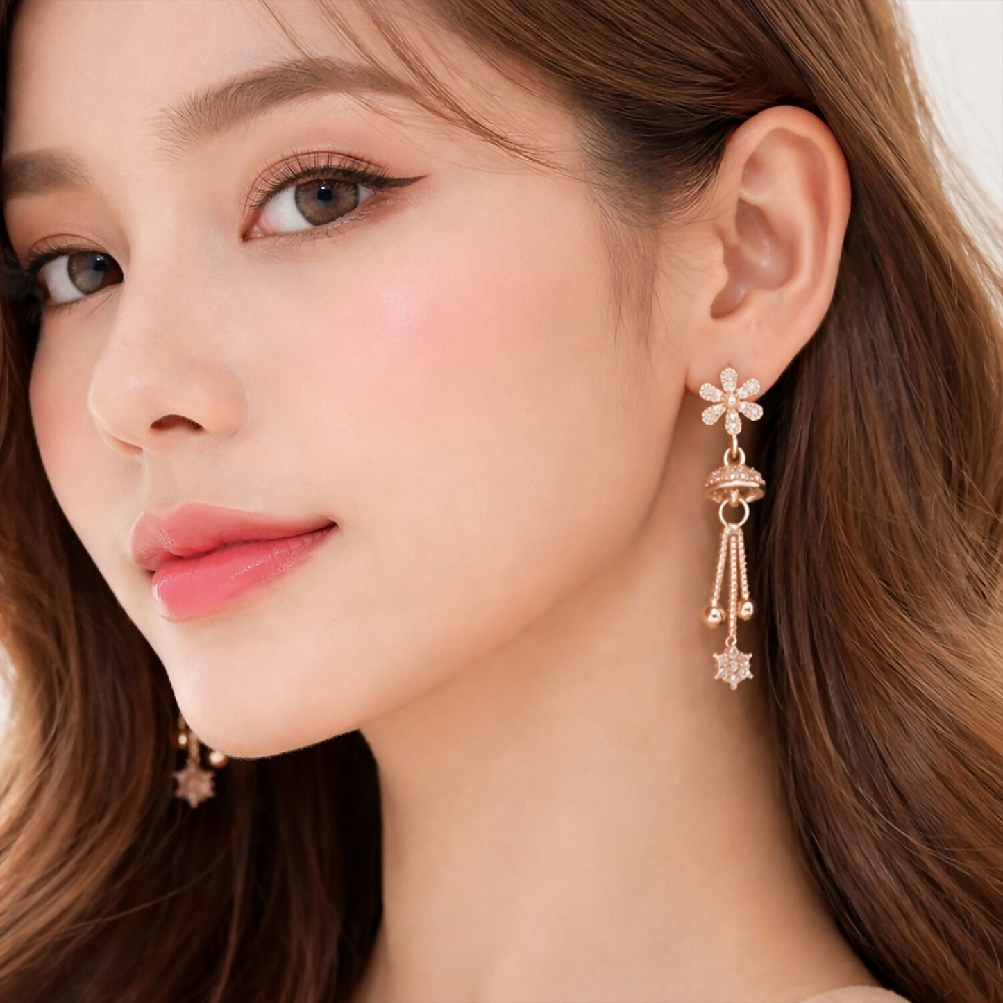 Close-up of rose gold drop earrings with crystal pavé floral starburst