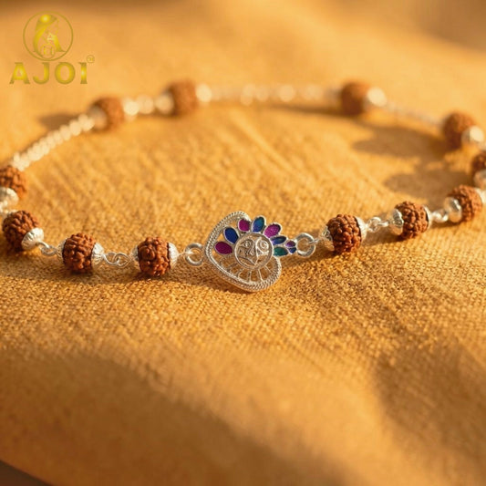 A silver bracelet with brown rudraksha beads and a central silver heart charm with colorful enamel accents rests on a yellow