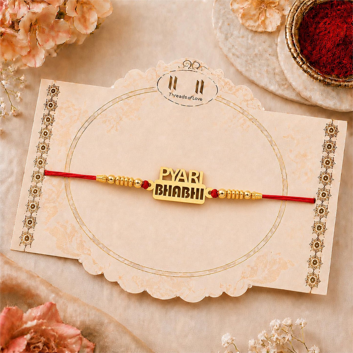 A close-up of a gold-colored bracelet with the words "PYARI BHABHI" on a decorative cream-colored card with gold accents.
