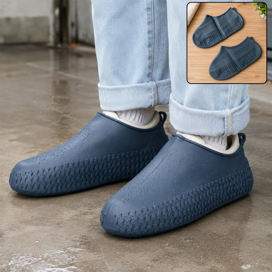 A person wears navy blue silicone shoe covers over their shoes, standing on a wet surface with two covers shown in an inset.