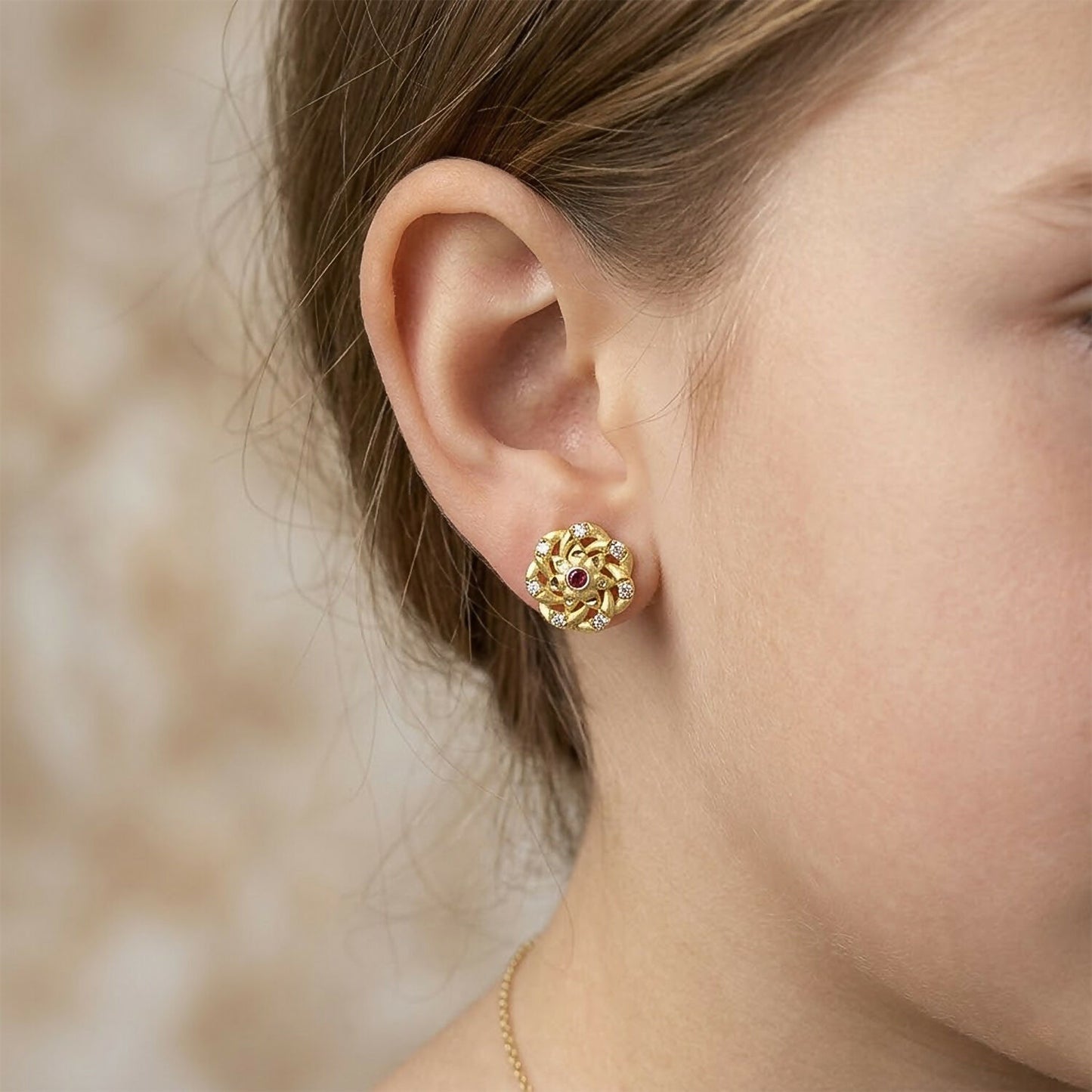 Elegant gold stud earrings featuring intricate floral design with sparkling accents