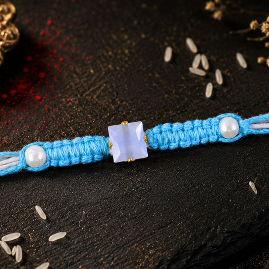 Close up of blue square stone macrame rakhi with pearl beads and silver accents.