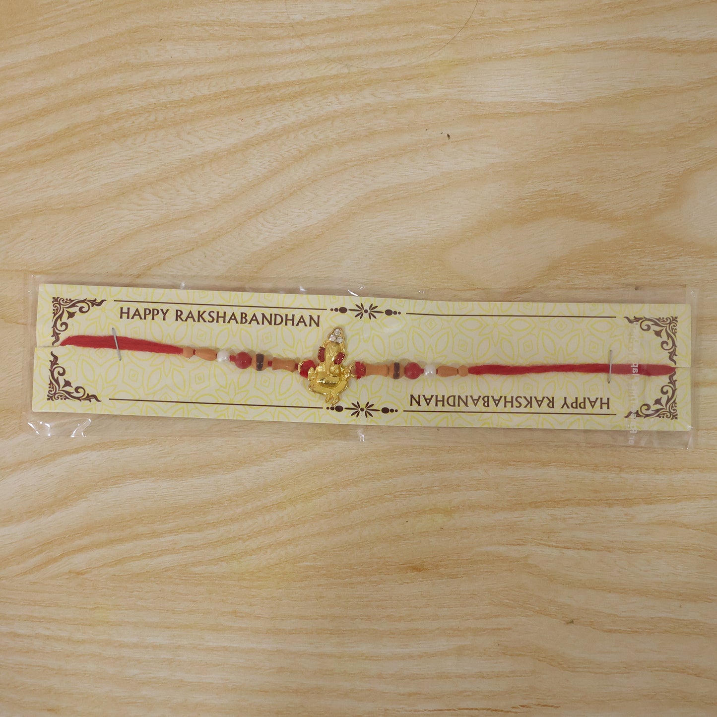 Golden Ganesha Rakhi with Peach Beads and Pearl Accents