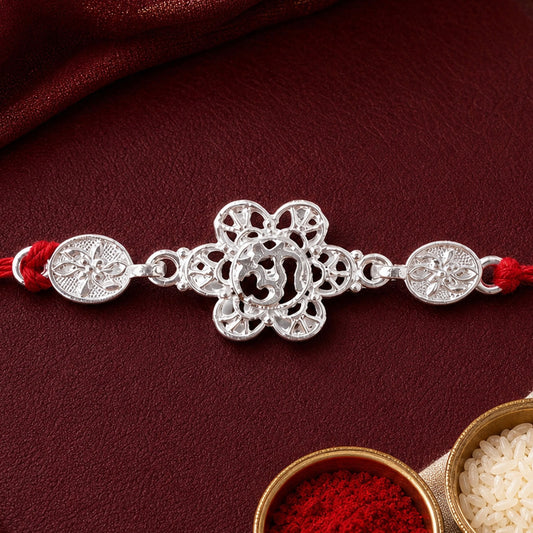 Silver Floral Om Rakhi with red thread on a white background, ready for Raksha Bandhan celebrations.