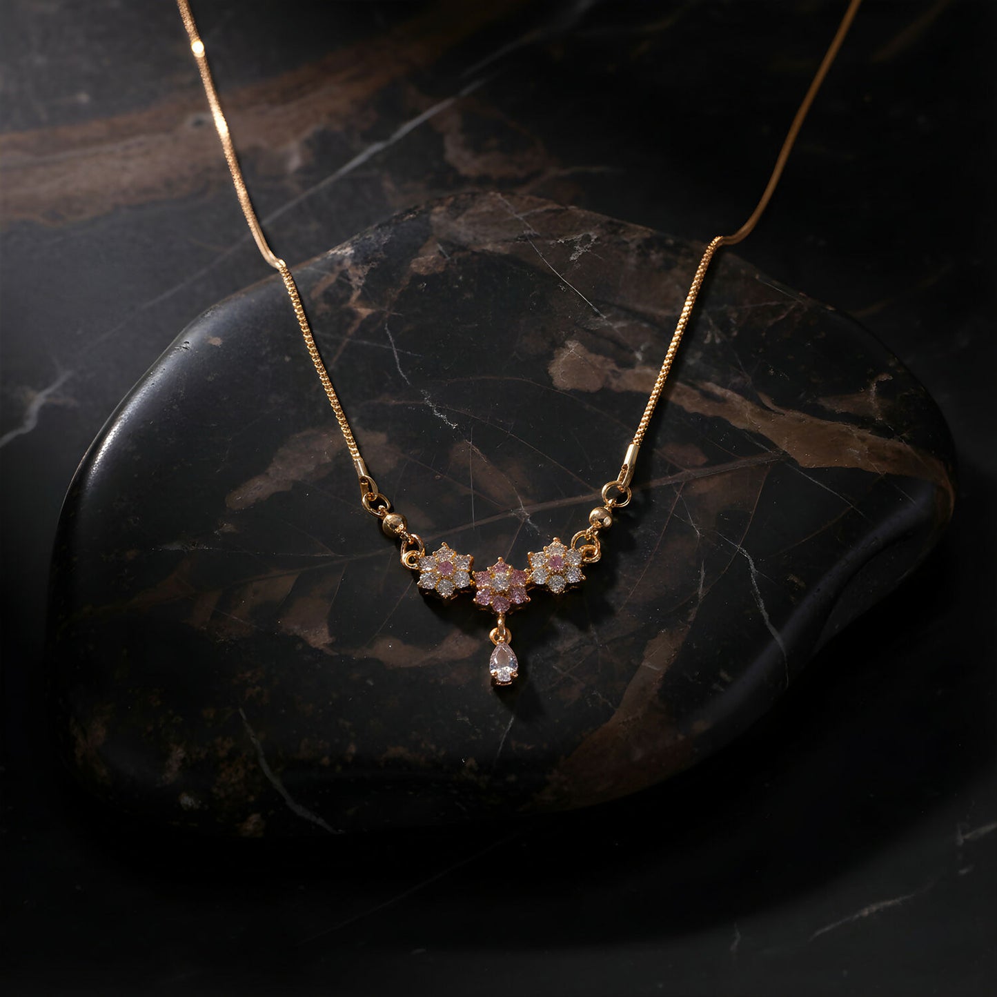 Closeup of elegant floral stone necklace with gold finish and teardrop pendant