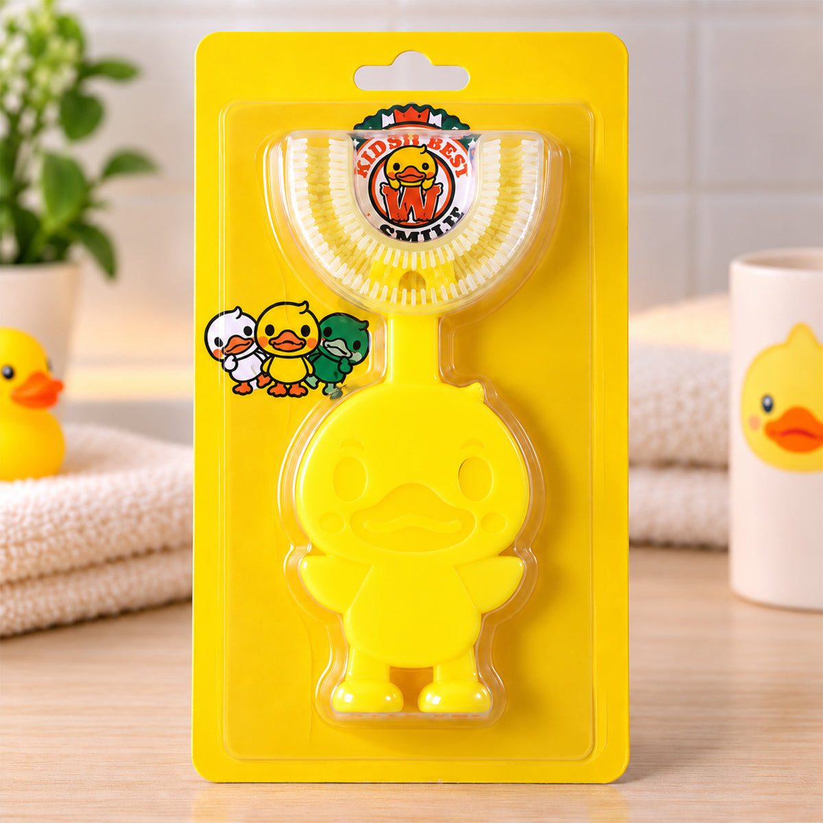 A yellow duck-shaped U-shaped toothbrush in clear plastic packaging with a yellow cardboard backing.